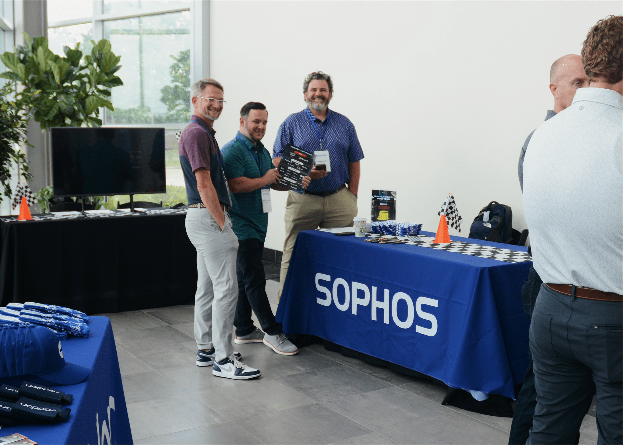 Sophos representatives standing in fron of their booth while showing off the IT Summit Kneed to Know flyer.