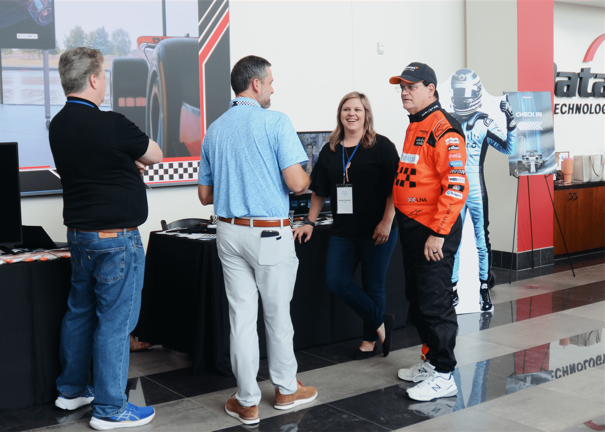 Cisco representatives speaking to executive dressed in Formula 1 race car driver gear.