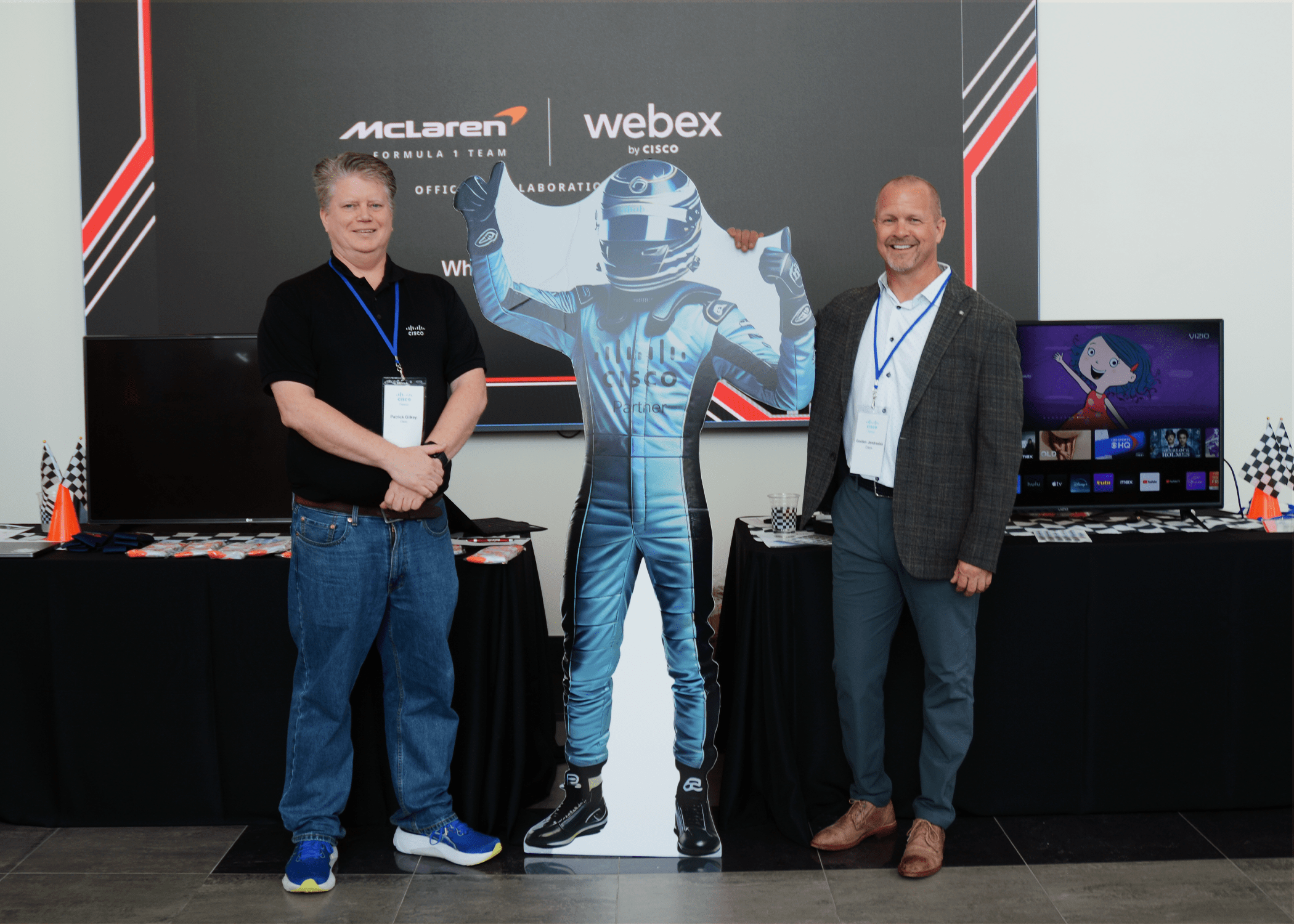 Cisco representatives standing next to Cisco race car driver cut-out.