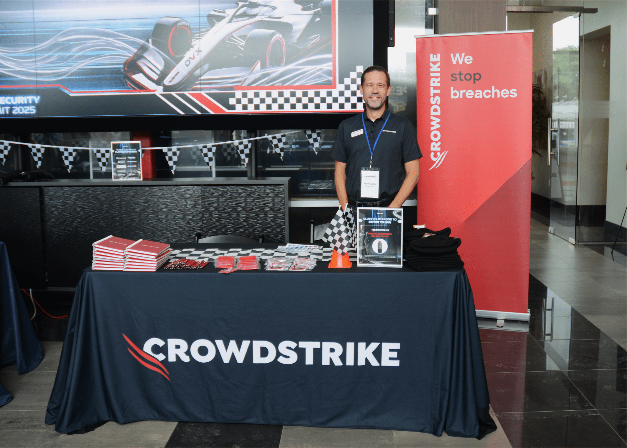 CrowdStrike representative standing behind his booth smiling at camera.